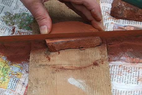 Het zagen van de eerste strook uit een plak rood natuurkrijt